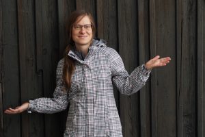 Cornelia Brückner im Regenmantel vor Holztür